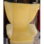 A 1960s G-Plan style wing armchair upholstered in gold dralon on black tapering legs.