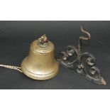 A polished bronze bell, 19th century, height 17cm, diameter 17.5cm and a wrought iron wall bracket.