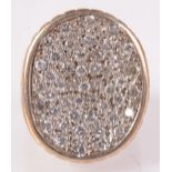A heavy 9ct gold ring the oval face set multiple diamonds.