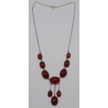 An Arts and Crafts silver and carnelian necklace with seven graduated carnelian cabouchons