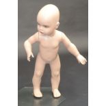 A mid 20th century shop display mannequin of a young child, on an octagonal glass base,