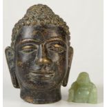 A metal Buddha's head, height 11.5cm and a hardstone seated buddha, possibly jade, height 3.5cm.