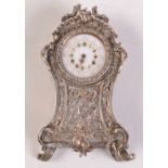 An ornate miniature French clock in Louis XV style, the case in silver and mother of pearl.
