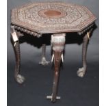 An Indian carved ebonised, octagonal table on four elephant head and trunk legs.