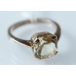 A silver ring set a pale yellow emerald cut stone.