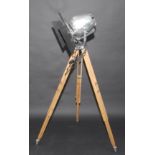 A Rank Strand metal spotlight on a wooden tripod stand, height 149cm.