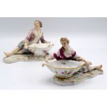 A pair of Meissen figural salts, modelled as a reclining couple with oval dishes,