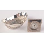 An oval half fluted dish and a quartz timepiece in a square planished case.
