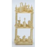 A miniature Anglo Indian ivory whatnot, the shelves covered with bottles, candlesticks, jugs,