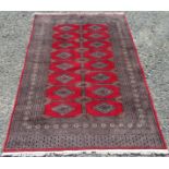 A Pakistan rug, the red field with eight rows of two stepped medallions, within multiple borders,