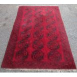 An Afghan carpet, the red field with seven rows of three large octagonal medallions,