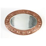 A good Newlyn Copper mirror, the oval frame with unusual decoration of chrysanthemum flowers,