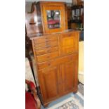 An early 20th century oak dentist cabinet topped with a mirrored cupboard door,