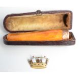 An amber, gold mounted cheroot holder and an enamelled 9ct gold naval crown brooch.