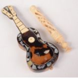 A tortoiseshell miniature guitar, length 13.5cm and a pierced bone sewing implement, length 10cm.