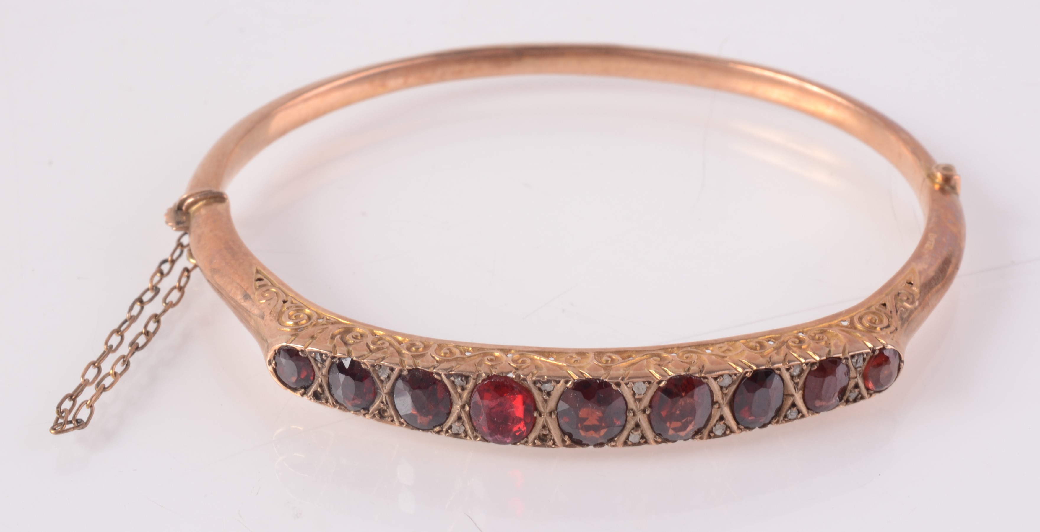 A 9ct gold Victorian style bangle set nine graduated garnets separated by tiny diamonds,