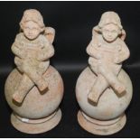 A pair of modern terracotta finials each with a winged cherub playing a harp, height 46cm.