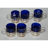 A set of six pierced silver cup holders with five blue glass liners.