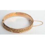 A 9ct gold bangle decorated with a flowering trellis, 11g.