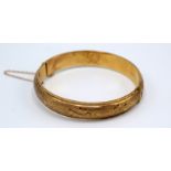 A 9ct gold bangle with foliate engraving, 17.5g.