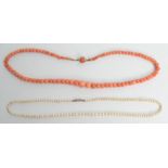 A pearl necklace with diamond set gold clasp and a coral necklace.