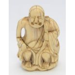 A Japanese ivory netsuke of a seated Rakan, holding his robes at his shoulder and knee,