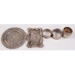 Three silver napkin rings, a small Indian silver tray and an Edwardian silver ring tray.