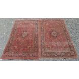 A pair of Kashan Persian rugs, each with a madder field and polychrome lobed medallion,