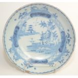 A Delft blue and white pottery bowl, 18th century, decorated with a riverside scene with pagodas,