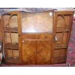 A 1930s walnut veneered cabinet with a slope front above a drawer and cupboard flanked by glazed