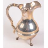 An Edwardian silver Georgian style bellied jug of unusual size on three legs with trefoil feet,