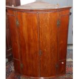 A George III oak hanging bowfront corner cupboard with blind doors.