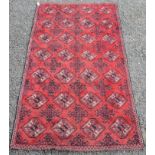 An Afghan rug, the red field with seven rows of four hexagonal medallions and rows of serrated guls,