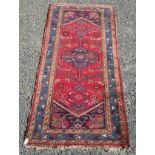 A Hamadan long rug, north west Persia, the madder field with a central indigo hexagonal medallion,