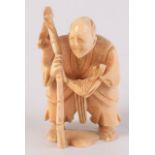 A Chinese carved ivory netsuke, an elderly gentleman carrying a bamboo cane with fish,