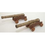 Two brass model cannons, mounted on wooden carriages, total length 26cm, height 9.5cm.