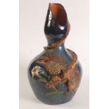 A large Brannam style earthenware glazed vase, decorated with a dragon holding an iris,