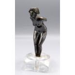 A white metal car mascot in the form of a naked lady mounted on a perspex base, height 16cm.