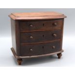 A miniature mahogany bow front chest of drawers, with three long drawers on bun feet, height 18.