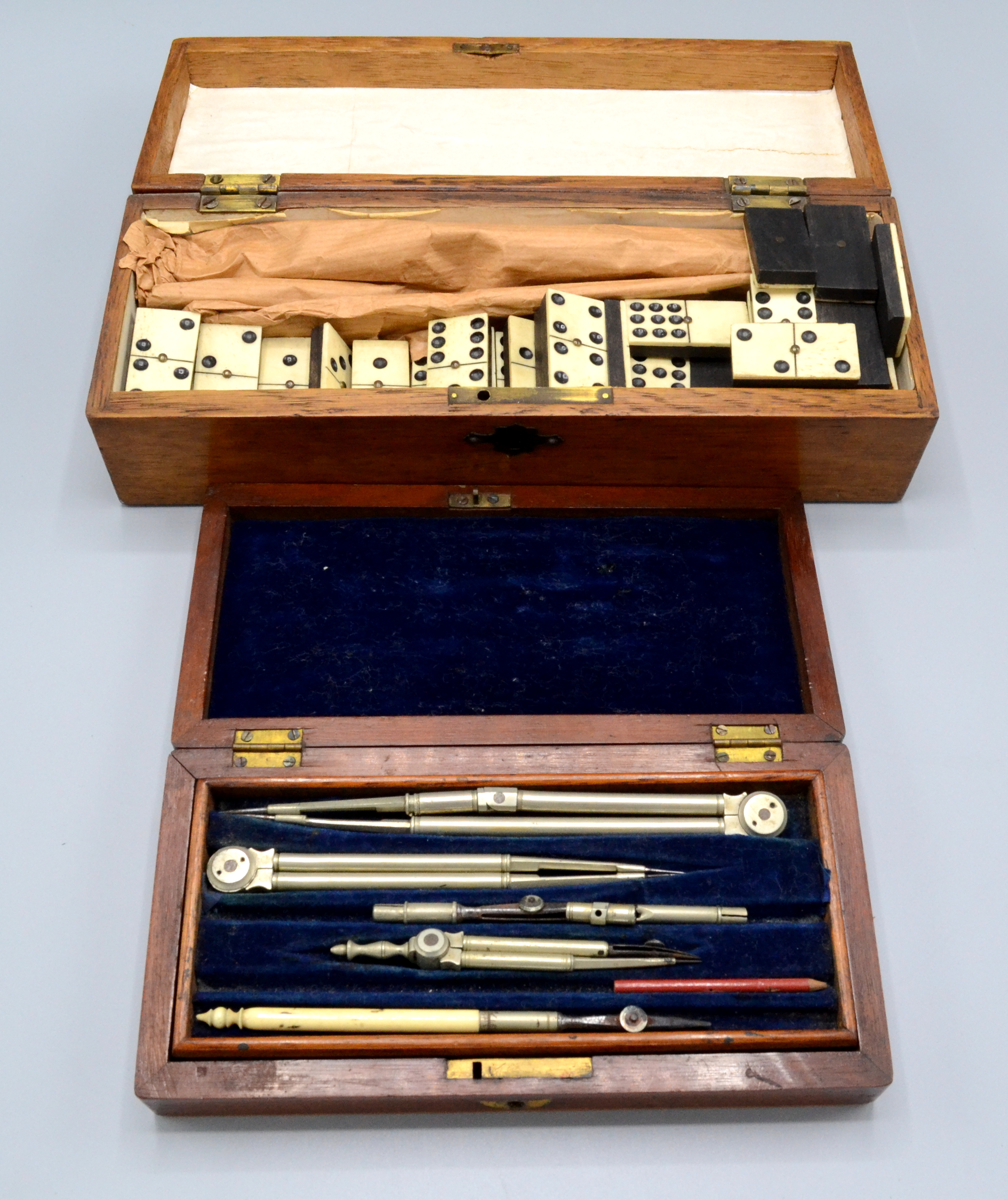 A boxed set of bone and ebonised dominoes and a mahogany cased set of drawing instruments.