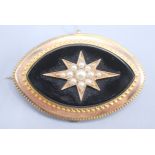 A Victorian gold elliptical brooch with pearl set central star on black onyx.