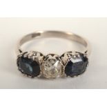 An 18ct white gold ring set a central diamond flanked by sapphires.