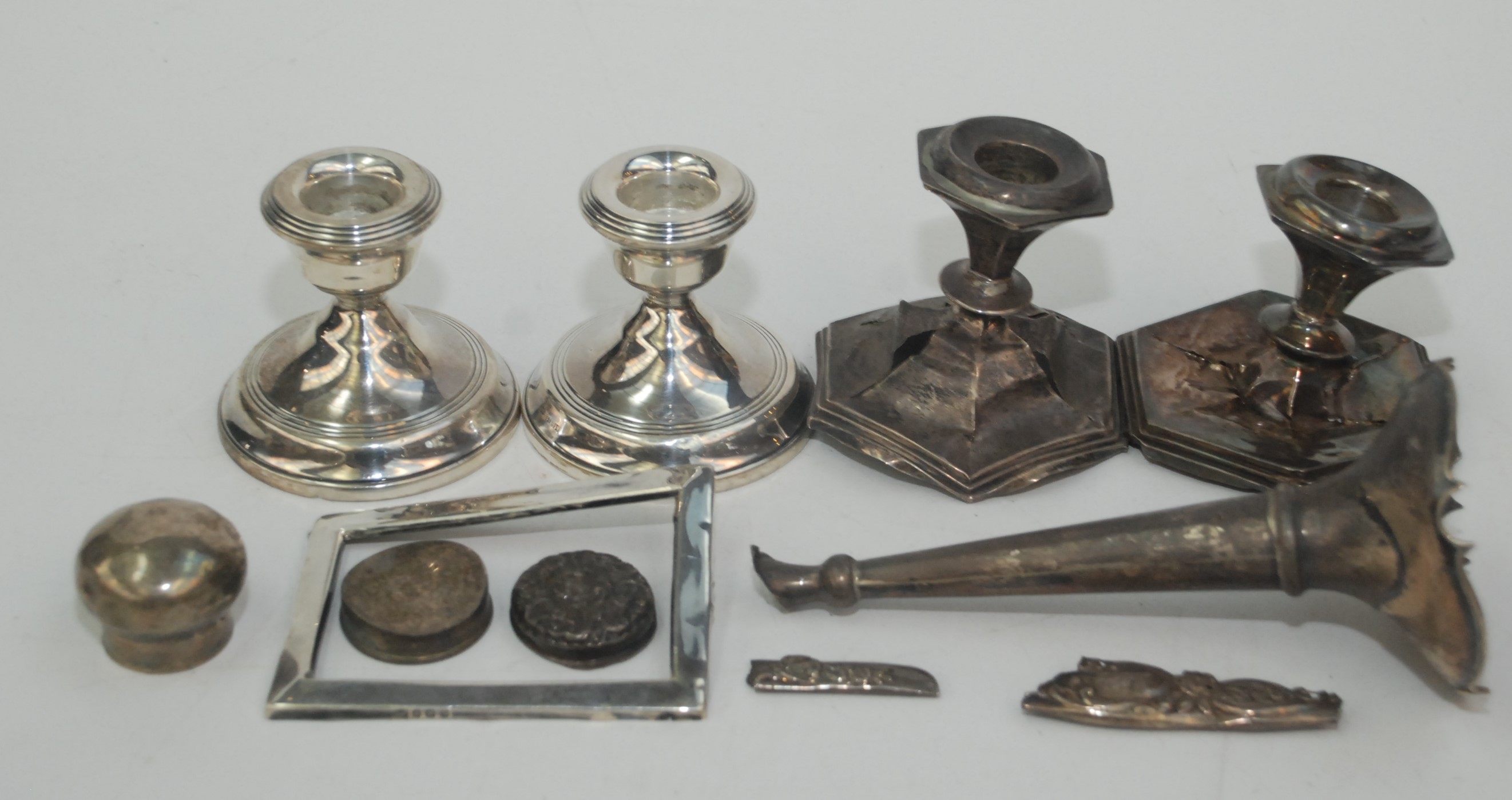 A pair of low filled silver candlesticks together with scrap silver.