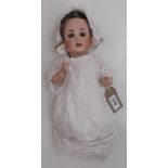 A porcelain head doll by Schuetzmeister and Quendt, the porcelain head with sleep eyes, open mouth,
