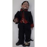 A ventriloquist's dummy with papier mache head, wood arms and fabric feet,