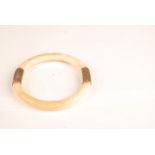 An ivory bangle mounted with two plain 18ct gold bands