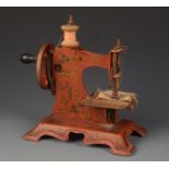 A late 19th/early 20th century die cast metal miniature sewing machine with gilt decoration on an