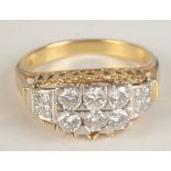 An 18ct gold ring set with a group of six diamonds each shoulder with four smaller diamonds.