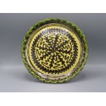 A Paul Young slipware pottery plate, the yellow glaze decorated with brown stylised leaves,