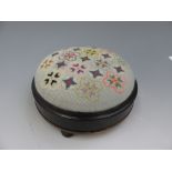A Victorian ebonised and gilt metal footstool with a circular needlepoint top on bun feet,